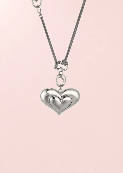 Sandy Heart necklace with a grey cord, shown on its composite pink background